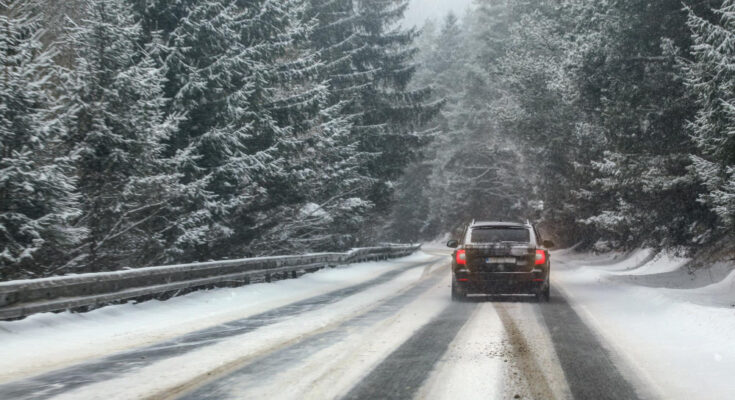 Black Car Drives Snow Covered Forest Road During Snowstorm Trees Both Sides View From Car Dangerous Driving Conditions