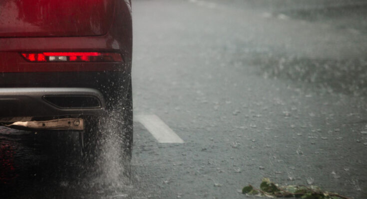 rain-water-splash-flow-from-wheels-red-car-moving-fast-daylight-city-with-selective-focus
