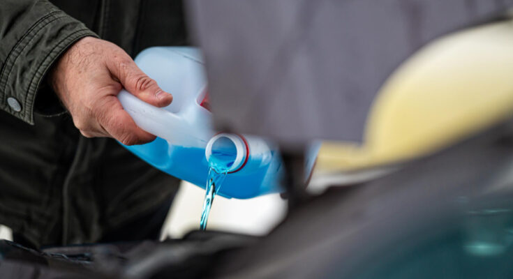 Driver Refilling Blue Nonfreezing Windshield Washer Liquid Tank Car Closeup